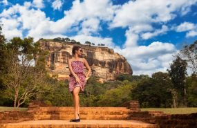 Young woman in sunglasses posing in front Sigiriya rock fortress at Sri Lankan sight